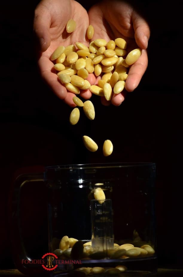 Soaked and pealed almonds being placed in mixer jar.