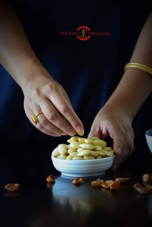 Soaked and pealed almonds being placed in a dish.