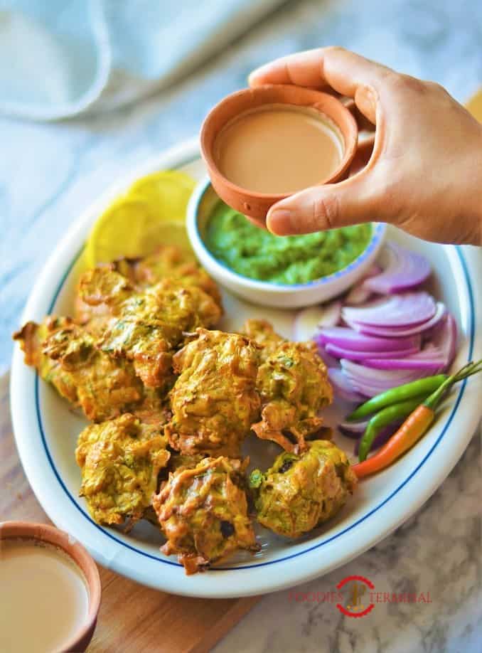 Chicken Pakora air fryer served with tea along with cilantro chuntney, onion slices, green chilies & lemon slices