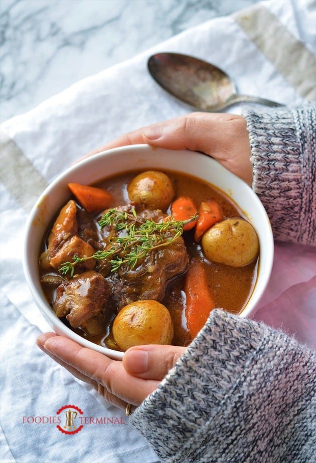 Hands holding a warm bowl of Lamb stew