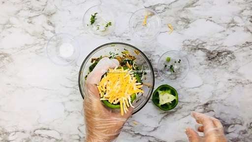 topping the stuffed pepper with shredded cheese