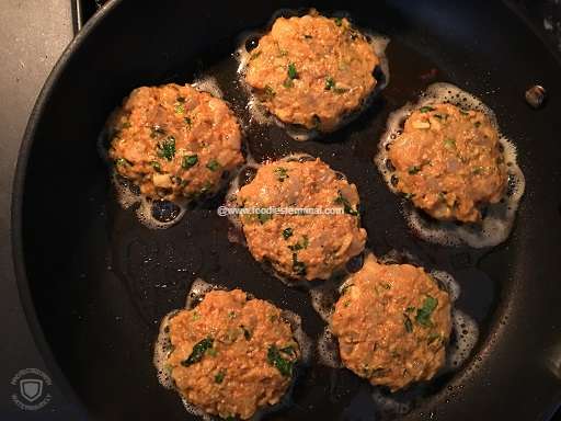 Patties on a black skillet being fried