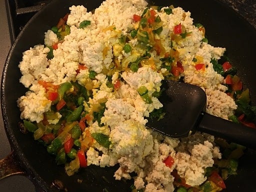 Tofu scramble being cooked in a black skillet