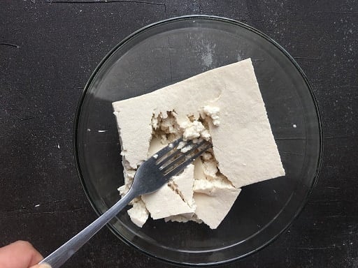 Tofu slab being scrambled with a fork