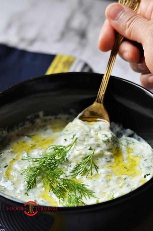 Best Tzatziki sauce recipe being lifted with a spoon from a black bowl