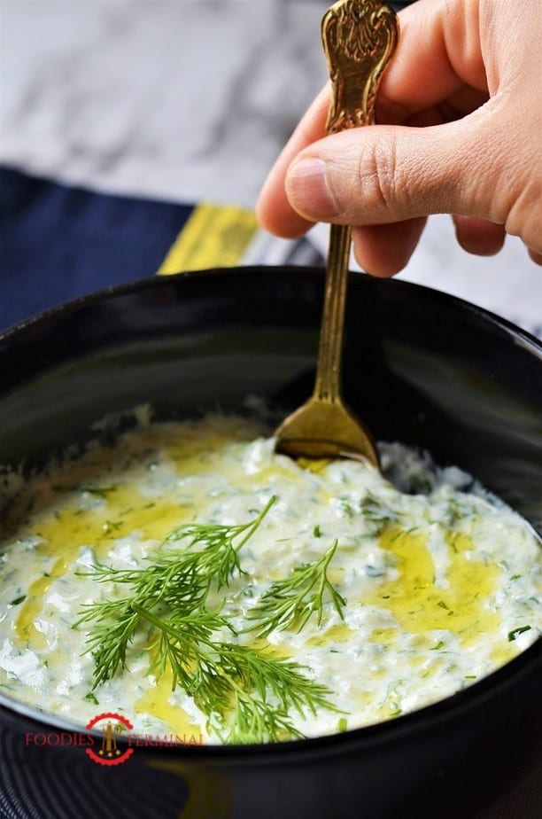 Authentic Greek Tzatziki Sauce in a black bowl with a brass spoon