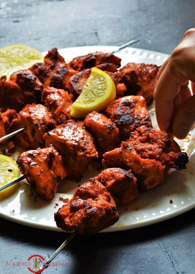 Chicken Boti Kabab skewer being lifted from the white plate