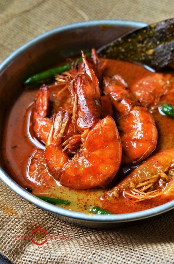 Chingri Macher Malai curry cooked with tiger prawns served in a white metal plate