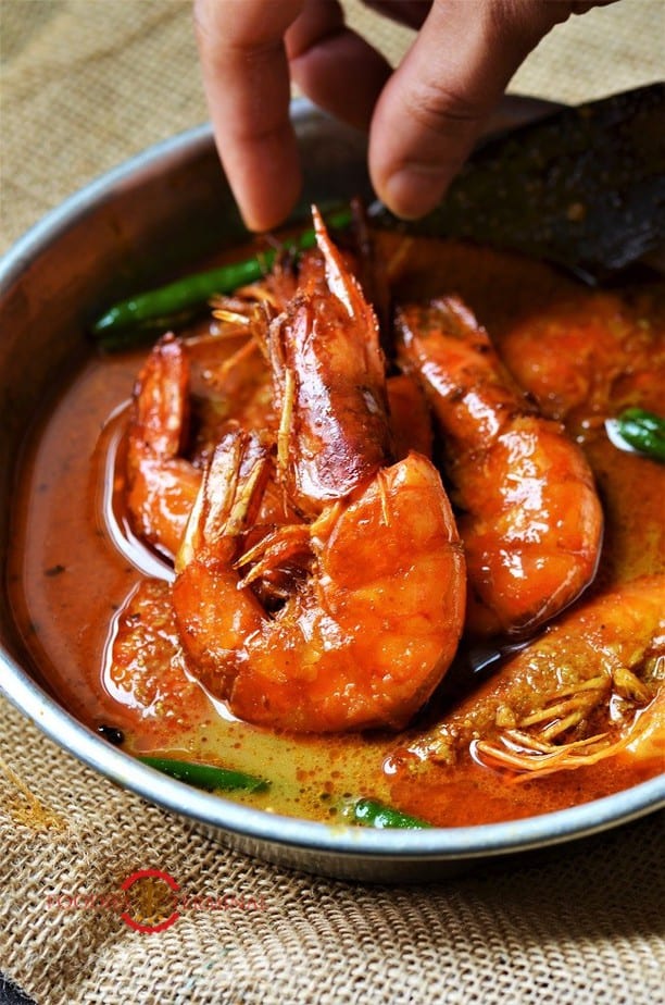 Chingri Macher Malai Curry in an aluminum plate with green chilies