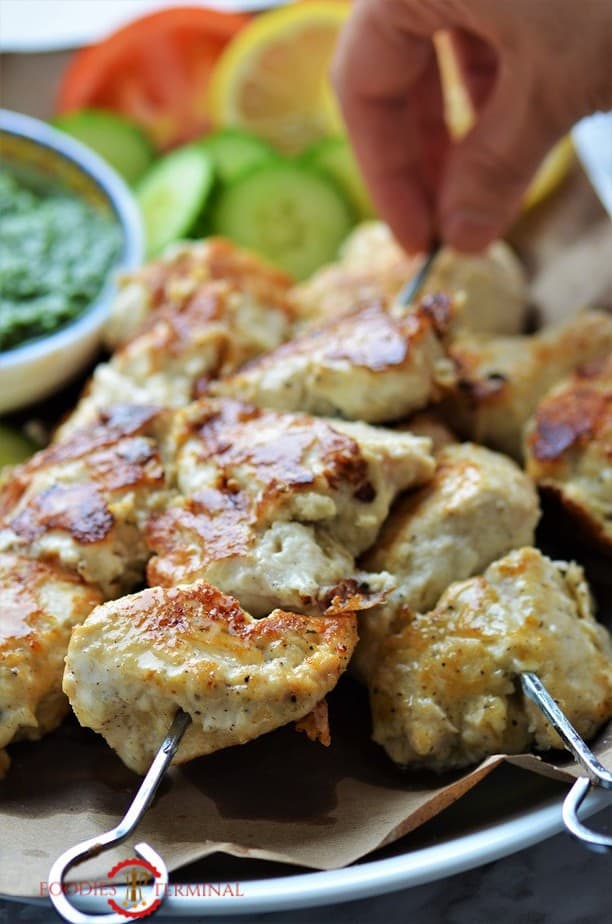 chicken malai tikka on metal skewers & being lifted