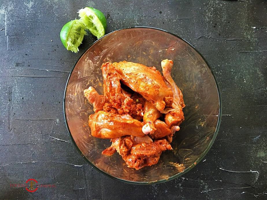 marinated chicken pieces in a transparent bowl on a black surface