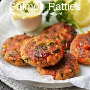 Salmon patties stacked on a white plate