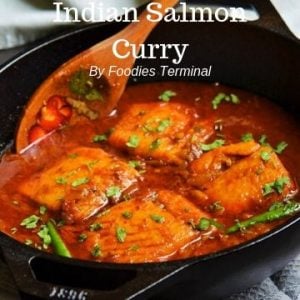 Indian Salmon curry in an iron wol with a wooden spatula