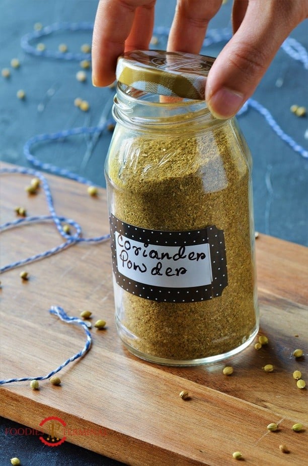 Dhaniya Powder recipe in a transparent jar with coriander seeds in the background