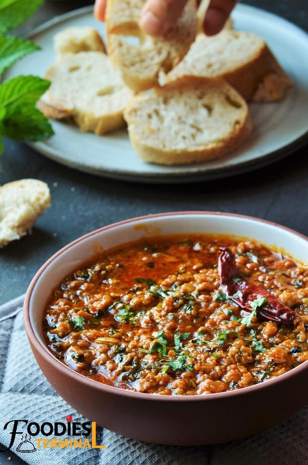Chicken keema in a bowl served with sliced baguette