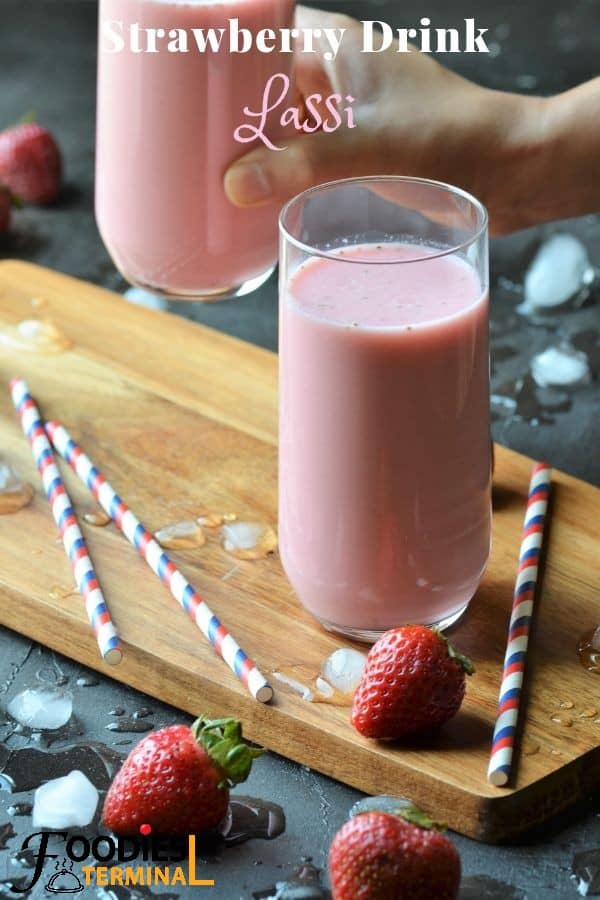 Strawberry Lassi in a glass with straws & berries by the side