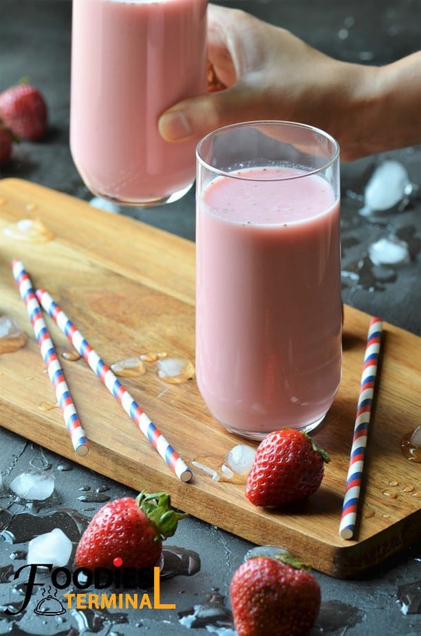 Creamy strawberry lassi recipe in a glass on a wood board