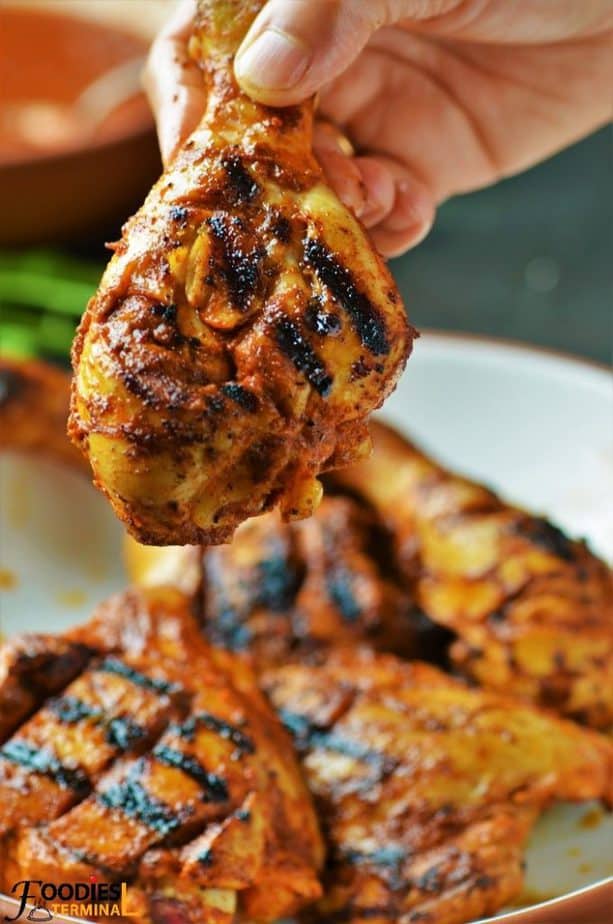 Spicy peri peri chicken roast drumtick being lifted