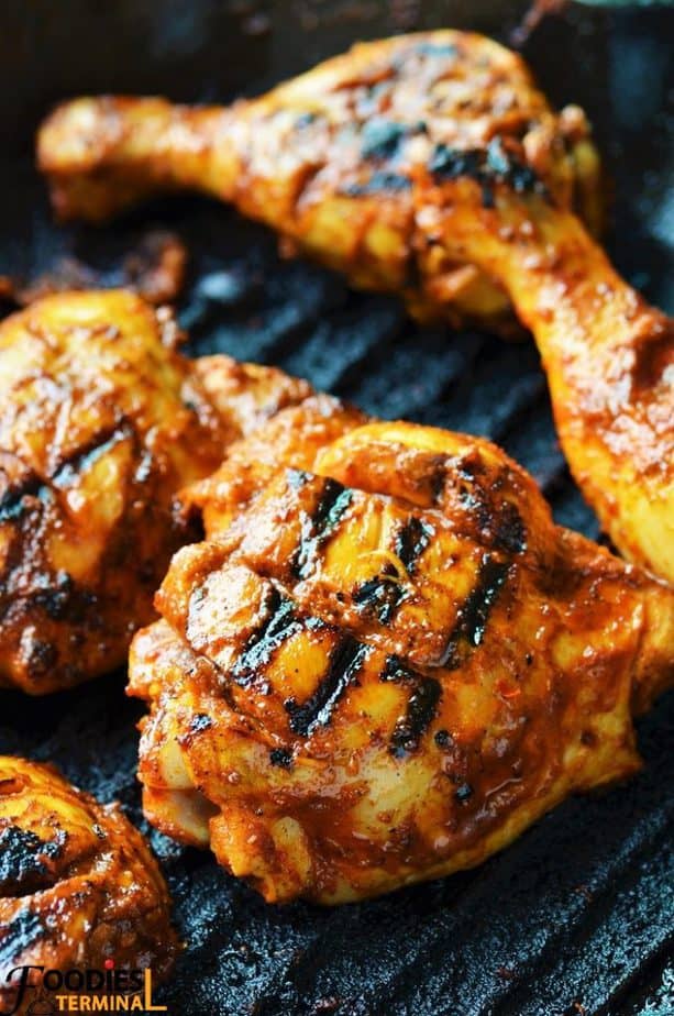 Portuguese peri peri chicken being roasted on a skillet grill