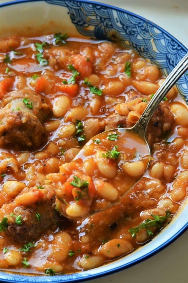 Sausage and white bean stew being spooned out 