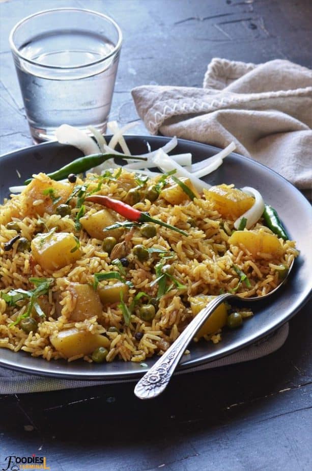 Aloo Matar Pulao on a black plate with onion slices