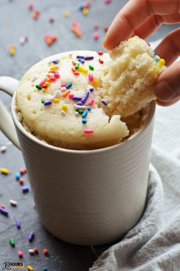 fluffy eggless vanilla mug cake being eaten from mug