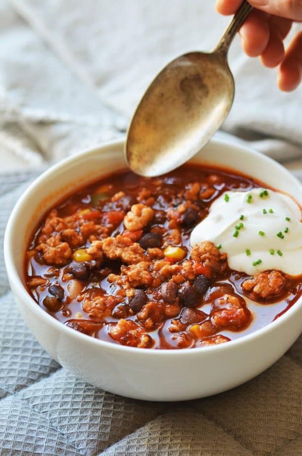 Turkey black bean corn chili in white bowl with cream