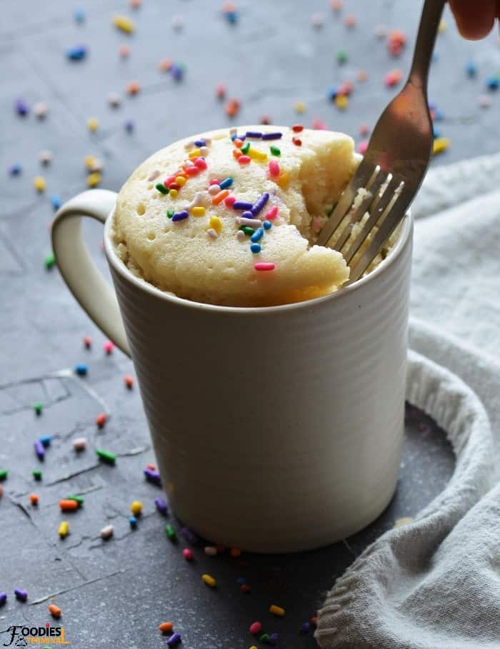 easy microwave vanilla mug cake in a cup being cut with fork