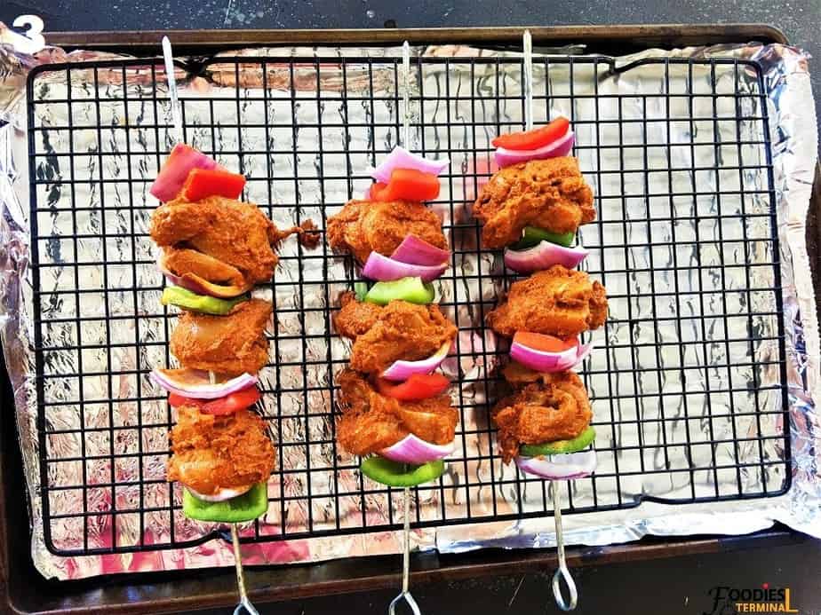 Skewered chicken tikka on an aluminum lined baking tray