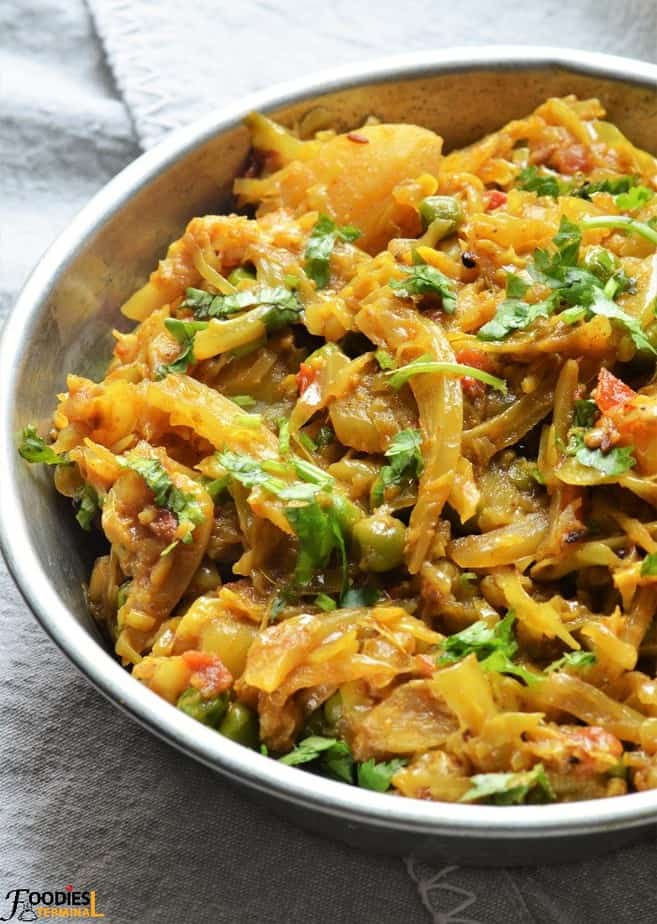 Cabbage Curry with peas and potato garnished with cilantro in a metal plate