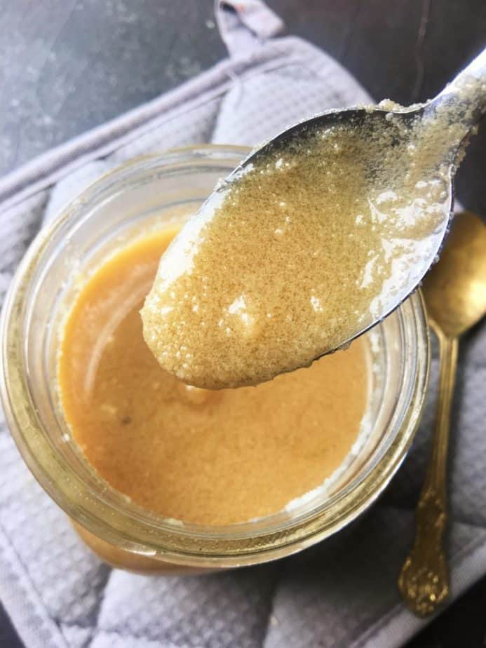 ghee in semi solid state scooped with a spoon from a glass jar