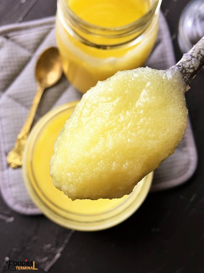 homemade traditional grainy ghee in two jars and a spoon