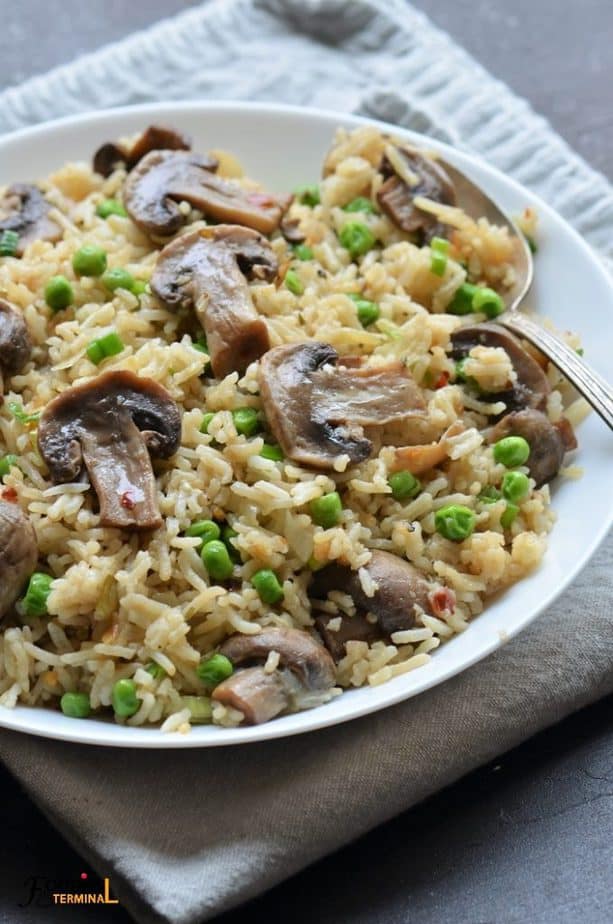 Instant Pot mushroom rice pilaf with white button mushrooms & peas in a white bowl
