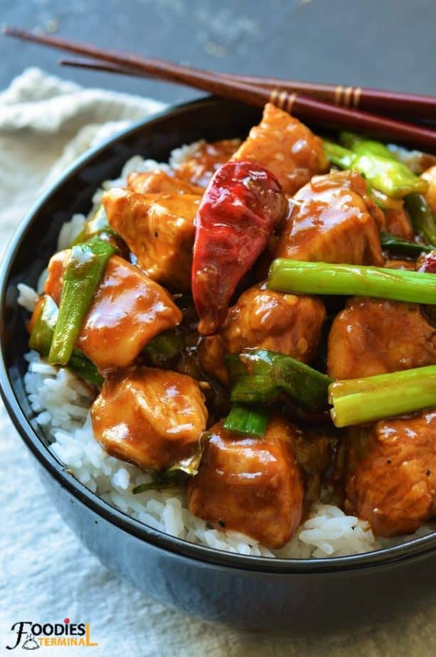 Instant Pot Mongolian Chicken on top of white rice in a black bowl with chopsticks
