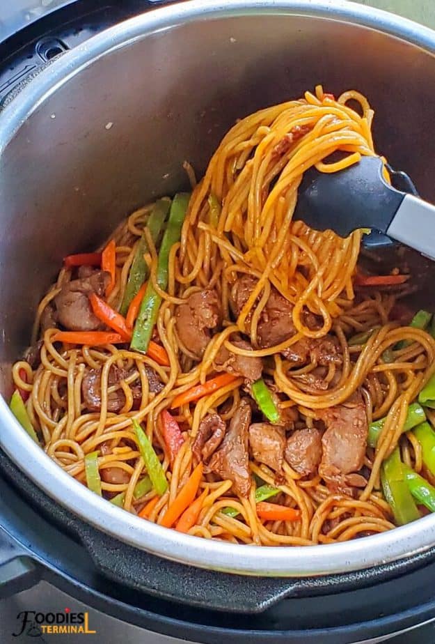 Pork Lo Mein in Instant Pot being lifted with a tong