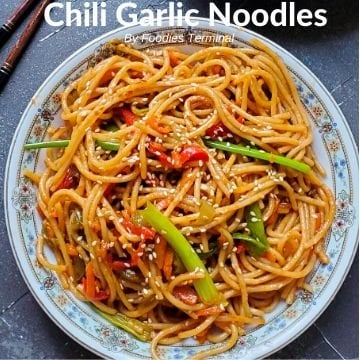 Chili Garlic Noodles garnished with white sesame seeds & served in a white plate