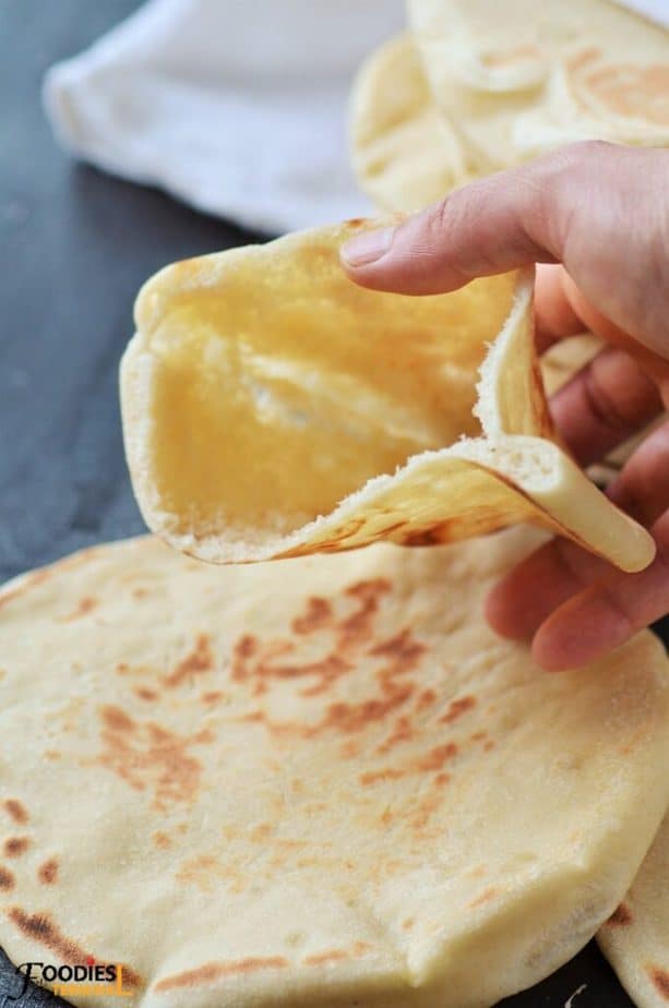 Homemade pita pocket bread in hand with pocket wide open