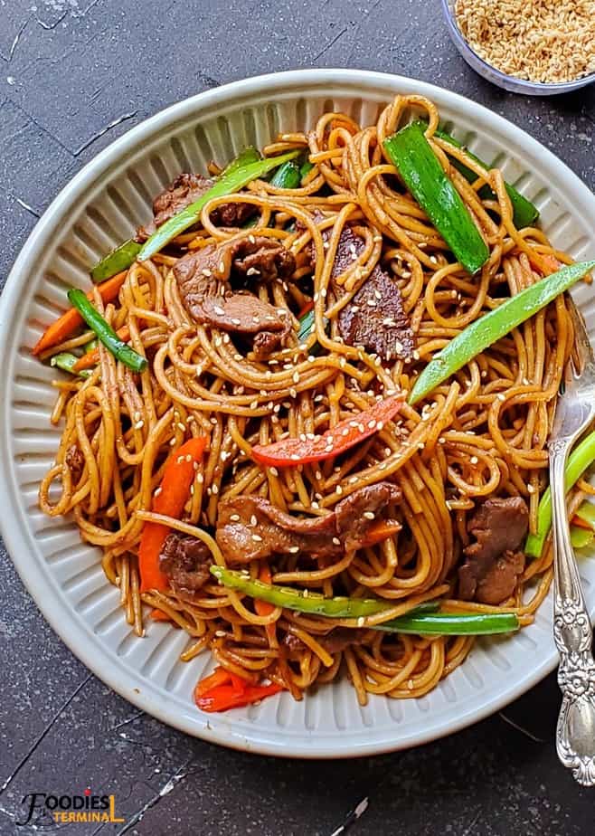 Instant Pot Pork Lo Mein in a beige bowl with a silver fork