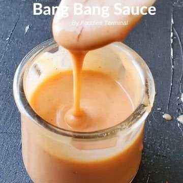 bang bang sauce dripping from a spoon in a transparent jar