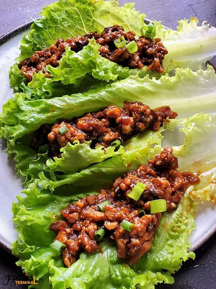 three chicken lettuce wraps assembled and served on a grey plate