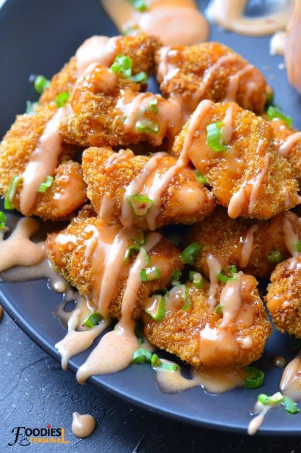 instant pot bang bang chicken drizzled with bang bang sauce on a black plate