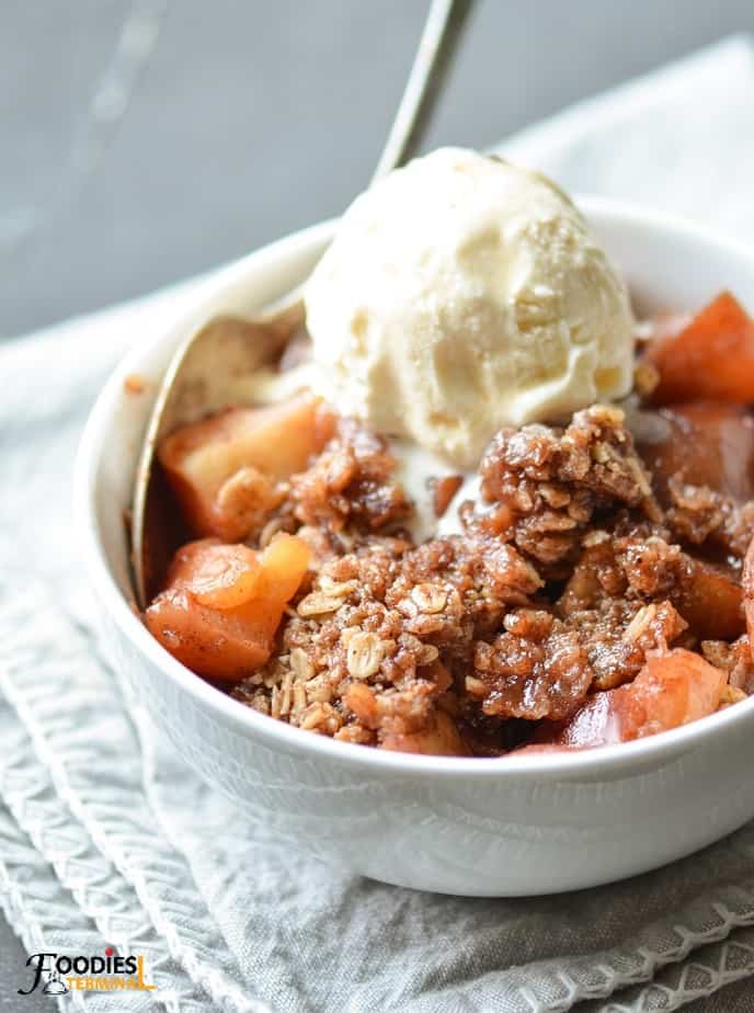 instant pot apple crisp served with vanilla ice-cream in a white bowl with a silver spoon
