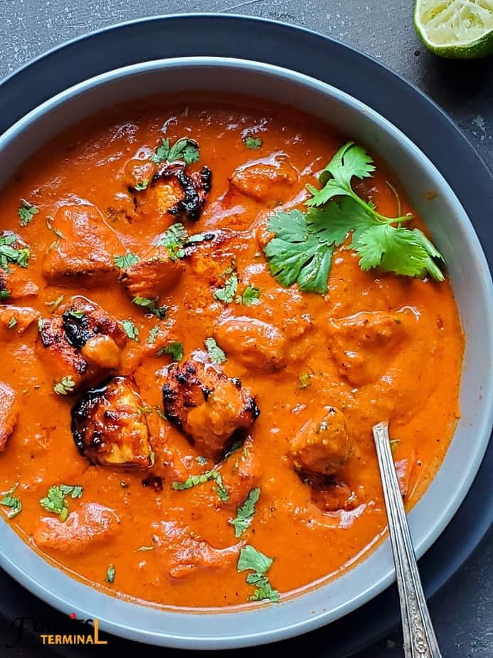instant pot chicken tikka masala in a grey bowl with a silver spoon & garnished with cilantro 