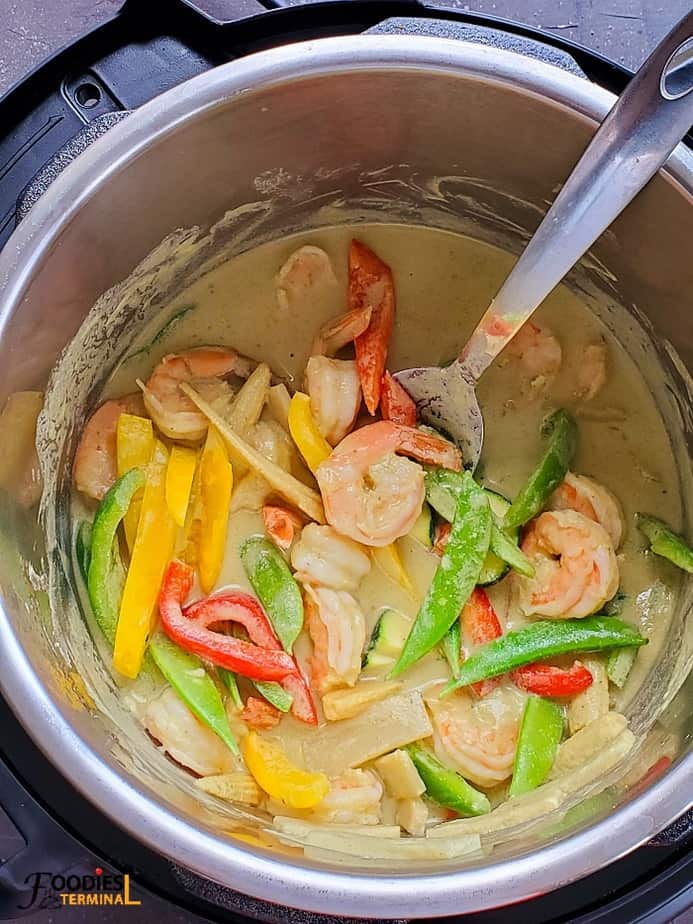 thai green curry shrimp with veggies in the instant pot with a ladle