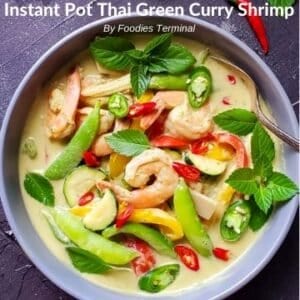 Thai green curry shrimp garnished with thai basil & chilies in a grey bowl