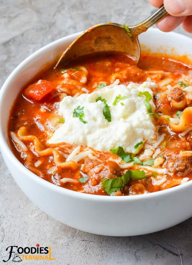Instant pot easy lasagna soup garnished with ricotta & mozzarella served in a white bowl with a spoon
