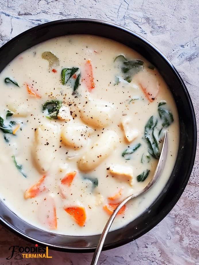 instant pot chicken gnocchi soup served in black bowl with a spoon