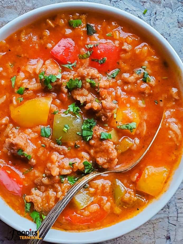 stuffed bell pepper soup with sausage in instant pot served in a white bowl with a spoon