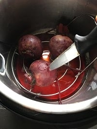 inserting a knife inside cooked beets to check for doneness
