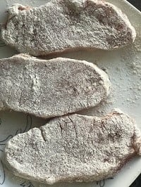 flour dredged boneless pork chops on a white plate